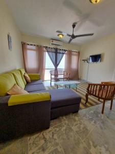 uma sala de estar com um sofá e uma televisão em Homestay α Cocobay Condo Resort em Porto Dickson