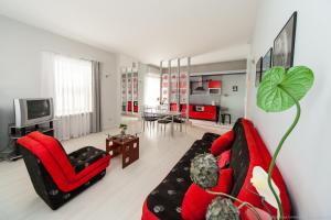 a living room with a red couch and a red chair at Apartamenti Alto & Ko in Jūrmala