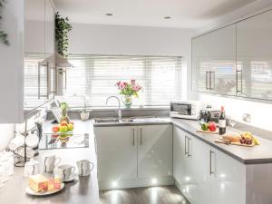 a kitchen with white cabinets and a sink at Seascape in Sheringham