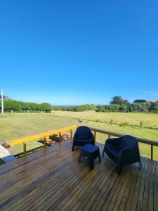 una terraza con 2 sillas, un banco y un campo en Cabañas Manzana 21 en Mar del Plata
