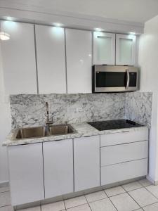 a white kitchen with a sink and a microwave at San Juan Apartments in San Juan