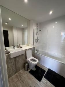 a bathroom with a toilet and a sink and a tub at Stylish 2 bedroom apartment Manchester City centre in Manchester