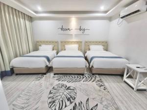 1 Schlafzimmer mit 3 Betten in einem Zimmer in der Unterkunft Hampton Suites in Davao City