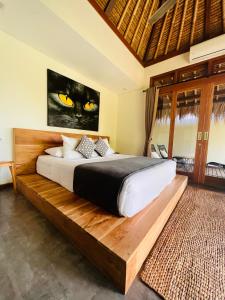 1 dormitorio con 1 cama con una pintura de gato negro en la pared en La Reserva Villas Bali, en Jimbaran