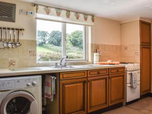 een keuken met een wastafel en een wasmachine bij Anneth Lowen in Perranwell