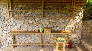 a stone wall with a wooden table and a stool at Elang Hillside Bamboo Villas in Labuan Bajo