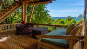 a porch with a bed and a view of the ocean at Elang Hillside Bamboo Villas in Labuan Bajo