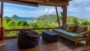 a porch with a couch and a view of the ocean at Elang Hillside Bamboo Villas in Labuan Bajo