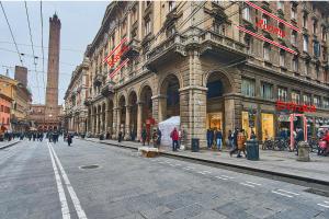 una strada cittadina con persone che camminano davanti a un edificio di Cuore di Bologna Suites a Bologna