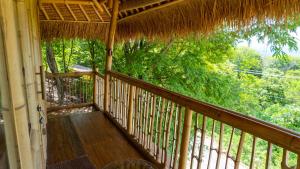 a porch of a house with a thatch roof at Elang Hillside Bamboo Villas in Labuan Bajo