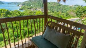 a bench on a balcony with a view of the ocean at Elang Hillside Bamboo Villas in Labuan Bajo