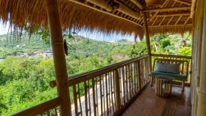 a porch with a blue chair on a straw roof at Elang Hillside Bamboo Villas in Labuan Bajo