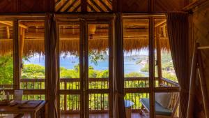 a room with a large window with a view of the water at Elang Hillside Bamboo Villas in Labuan Bajo