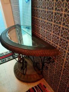 a glass table on a wooden stand in a room at Paradis in Dar Salah Bey