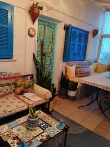 uma sala de estar com janelas azuis e um sofá e mesas em Paradis em Dar Salah Bey
