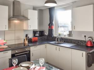 a kitchen with white cabinets and a table with wine glasses at Sea Breeze in Mossbay