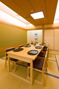 une salle de conférence avec une grande table et des chaises en bois dans l'établissement Kusatsu Estopia Hotel, à Kusatsu