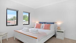 1 dormitorio blanco con 1 cama y 2 ventanas en Bluebell, en Bowral