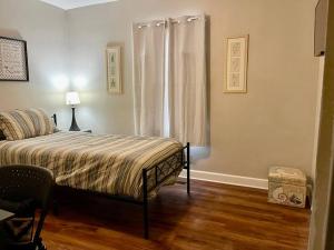 a bedroom with a bed and a chair and a window at Comfort by The University & Waterfront in Elizabeth City