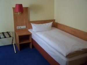 a small bedroom with a bed and a table at Hotel Gerber in Hösbach