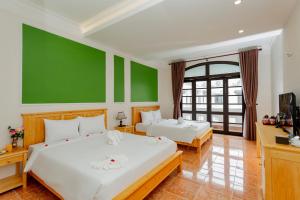 ホイアンにあるSea and Sand Hotelの緑の壁のベッドルーム1室(ベッド2台付)