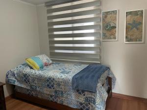 1 dormitorio con cama y ventana con colcha en Departamento Marina Peñuelas, en La Serena