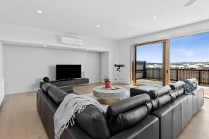 a living room with a leather couch and a television at REFLECTIONS at Lonsdale in Point Lonsdale
