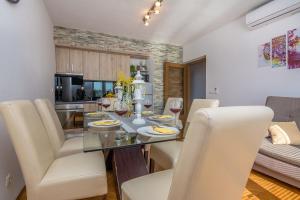 een eetkamer en een keuken met een glazen tafel en witte stoelen bij Apartment Radovic Nives in Vir