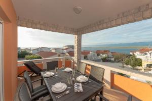 - une table à manger sur un balcon avec vue sur l'eau dans l'établissement Apartments Kovacevic, à Vir