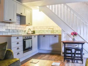 una cocina con armarios blancos y una mesa con sillas. en Primrose Cottage, en Grassington