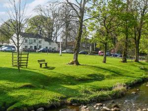 un parque con un banco en el césped junto a un río en Primrose Cottage, en Grassington