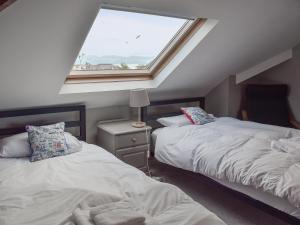 a attic bedroom with two beds and a window at Westville in Criccieth