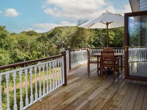 a wooden deck with a table and an umbrella at Teasel Lodge - Uk39647 in Lunga