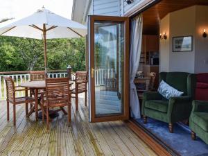 a deck with a table and chairs and an umbrella at Teasel Lodge - Uk39647 in Lunga