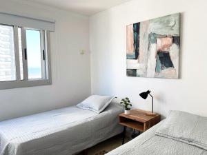 1 dormitorio blanco con 2 camas y ventana en South Beach Apartment, en Punta del Este
