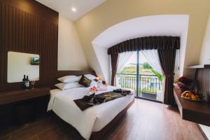 GREENECO DA LAT HOTEL - Khách sạn Green Eco Đà Lạt في دالات: غرفة نوم بسرير كبير ونافذة كبيرة