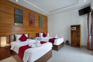 two beds in a room with wooden walls at Hotel Arsa Santhi Nusa Penida in Nusa Penida