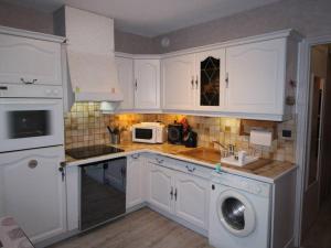 a kitchen with white cabinets and a sink and a microwave at Appartement Bagnères-de-Luchon, 2 pièces, 6 personnes - FR-1-313-218 in Luchon