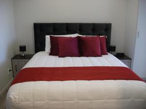 1 dormitorio con 1 cama grande con almohadas rojas en The Runaway en Dargaville