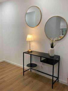 a table with a lamp and two mirrors on a wall at Cosy Apartment - lovely stay/ Free parking/ Netflix in Falagueira