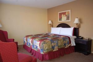 a hotel room with a bed and a chair at Golden Manor Inn & Suites in Muldraugh +31 photos