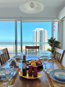 una mesa con una bandeja de frutas y botellas de vino en South Beach Apartment, en Punta del Este