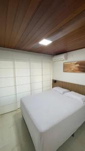 Cama blanca en habitación con techo de madera en Flat 705 Villa Hipica Gravata PE, en Gravatá