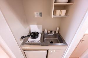 una pequeña cocina con fregadero en una pequeña habitación en Luana Hotel ベルビ早稲田, en Tokio