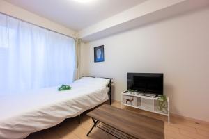 1 dormitorio con 1 cama, TV y mesa en Luana Hotel ベルビ早稲田, en Tokio