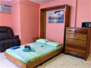a small bedroom with a bed and a dresser at Beach Club Condos at Popeyes in Caye Caulker
