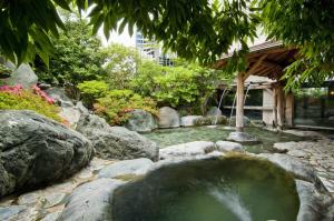 un estanque en un jardín con rocas y un árbol en Hotel Sekifu, en Fuefuki