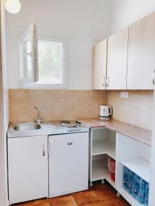 una pequeña cocina con armarios blancos y fregadero en Villa Elpiniki, en Troulos