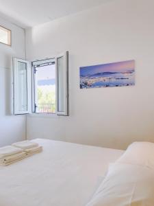 a white bedroom with a bed and two windows at Villa Elpiniki in Troulos