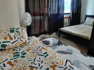 Family Staycation 2 with Pool في مانيلا: غرفة نوم مع سرير مع لحاف عليه